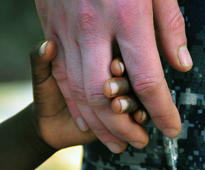 US Navy Ensign Adam Cole holds hands with a Haitian girl
